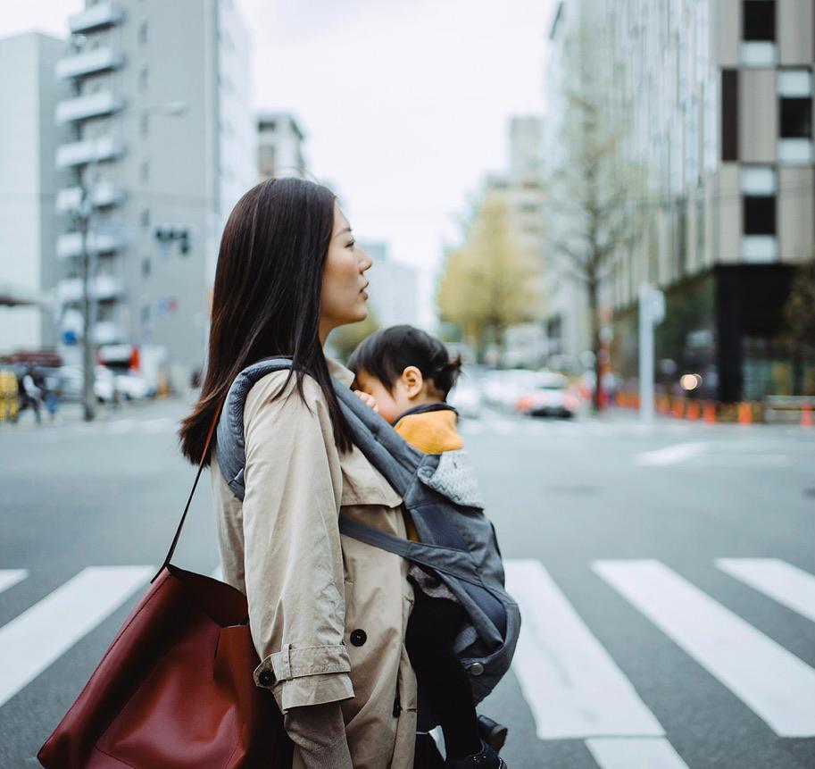 Sideways shot of a woman walking with sleeping baby in a baby carrier