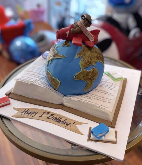 Close up of custom first birthday cake depicting a pilot in a red plane situated on top of a globe