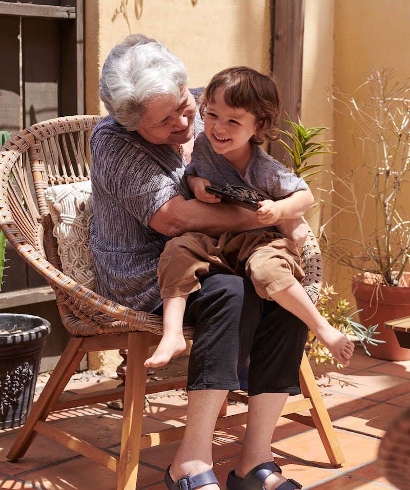 Older woman hugs a laughing grandson